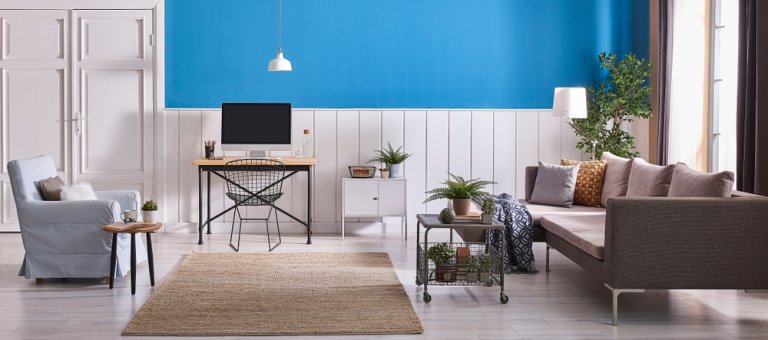 Modern Living Room White And Blue Wall Background Wooden Working Table Grey Sofa And Blue Armchair With Blanket. White Lamp And Green Plant 768x340 